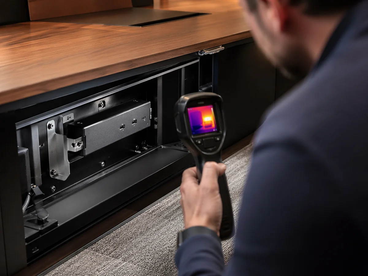 Ein Ingenieur prüft die thermische Leistung eines in ein geschlossenes Möbelstück integrierten USB-Lademoduls und untersucht die Wärmeverteilung und das thermische Verhalten in einer abgedichteten Integrationsumgebung.webp